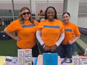 3 employee ombudsmen ladies standing in front of a table with books