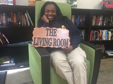 Girl in chair holding sign that reads The Living Room
